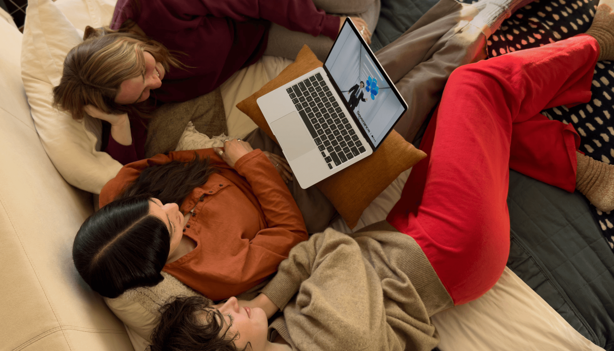 Three people on a couch watching full-screen video on MacBook Air